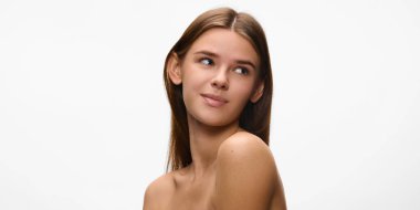 Çekici, güzel, çıplak omuzlu genç bir kadın ve beyaz stüdyo geçmişine bakıyor. Doğal güzellik kavramı, kendine özen, cilt bakımı, kozmetoloji bir kaplıca prosedürü. Ad