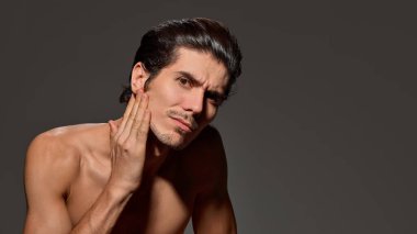 Adam hafifçe yukarı bakıyor, arka planda yumuşak bir gülümseme sergiliyor. Duruşu ve düzgün saç şekli rahatlık ve kendine güveni gösteriyor. Erkek güzelliği ve yüz bakımı kavramı, yaşlanma karşıtı prosedürler.