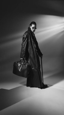 Tek renkli, yuvarlak gözlüklü ve deri ceketli vampirlerin uzun bir portresi çanta ve baston taşıyor. Karanlığın efendisi. Tarihsel ve modernlik kavramı, moda ve tarz, yaratıcılık.