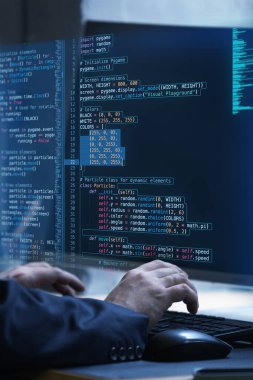 Eller klavyede kurgusal kod ekranı ile çalışıyor, programlamada insan yaratıcılığının ve problem çözmenin sanal etkileşimini temsil ediyor. Bilişim çözümleri, uygulamalar, programlama kavramı. Ad