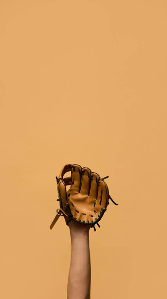 Рука носит кожаную бейсбольную перчатку, надежно держит мяч, представляет собой защиту и мастерство ловли на теплом фоне. Концепция спортивного инвентаря, управления, стратегии, игры. Объявление