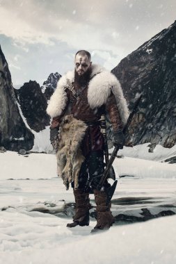 Karlı dağ manzarasında dikilen Viking savaşçısı savaş baltası ve kılıcıyla kürk pelerin ve deri zırh giymiş kararlı bir ifadeyle. Tarihi portre, İskandinav kültürü konsepti