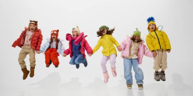 Kameraya doğru koşan bir grup çocuk, sıcak kışlık ceketler ve şapkalar giyip heyecanla bağırıyor, beyaz stüdyo arka planına karşı neşeli anın tadını çıkarıyorlardı. Çocukluk kavramı, kış tatili
