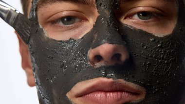 Erkek yüzüne yakın çekim, besin örtüsü, cilt bakımı maskesi, bakışları beyaz stüdyo arka planına doğru. Bencillik ve sevgi kavramı, doğal güzellik, kozmetoloji.