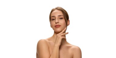 Çıplak omuzlu zarif bir kadının yatay fotoğrafı beyaz stüdyo arka planına dikkatlice bakarken nazikçe çenesine dokunuyor. Güzellik ve cilt bakımı, kendini sevme, zarafet, sağlık..