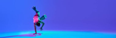 Dinamik genç bir adam, dansçı güçlü break dans hareketleri yapıyor, neon mavisi arkaplana karşı yetenek ve ritmi harmanlıyor. Hip-hop kültürü, hareket, sanatsal ifade ve gençlik enerjisi kavramı