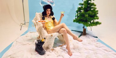 Mayo ve kış şapkalı şık bir kadın. Stüdyo arka planında kış temalı şampanyayı ve havyarı seviyor. Lüks yaşam tarzı kavramı, kış tatili kutlaması, konfor.