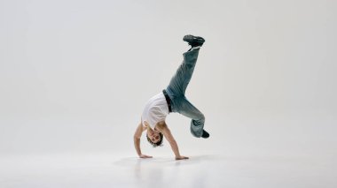 Etkileyici hareket sanatçısı el ele tutuşup serbest stil dans enerjisini beyaz arka plana karşı fiziksel limitleri zorluyor. Dinamik hareket kavramı, şehir tarzı, sanat, spor, yaratıcılık, müzik.
