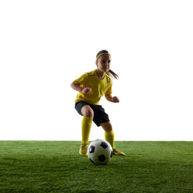 Sarı formalı, siyah şortlu futbol topu süren, beyaz arka planda çimenli zeminde ilerleyen bir kız. Spor, çocukluk, hareket, rekabet, etkinlik kavramı