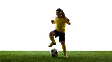 Genç bir kızın dinamik görüntüsü, futbol topuyla beyaz stüdyo arka planında futbol antrenmanı. Spor, çocukluk, hareket, rekabet, aktivite kavramı. Boşluğu kopyala