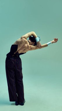 Heykel hareketinde kollarını büken etkileyici dansçı, akışkanlığı ve yapıyı vurgulayarak eskilerden esinlenerek yumuşak, minimal arkaplana karşı. Sanat anlayışı, zarafet, müzik, güzellik.