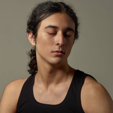 Yakışıklı bir genç adam portresi. Huzurlu bir yüz ifadesi, kapalı gözler, pürüzsüz bir ten ve geriye çekilmiş parlak siyah saçlar. Sağlık, rahatlama, kozmetik, erkek güzelliği, cilt bakımı, reklamlar.