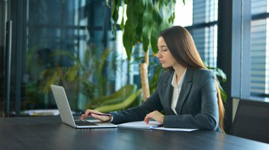 Dizüstü bilgisayarda yazan, verileri analiz eden ve modern çalışma alanında notlar alan odaklanmış bir iş kadını. Teknoloji kavramı, üretkenlik, kurumsal strateji, verimlilik.