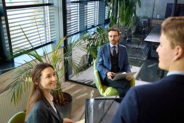 Yönetici, iyi ışıklandırılmış çağdaş ofiste fikirleri sunarken iş ortaklarıyla güven içinde konuşuyor. Liderlik kavramı, yönetim, kurumsal yenilik, vizyon.