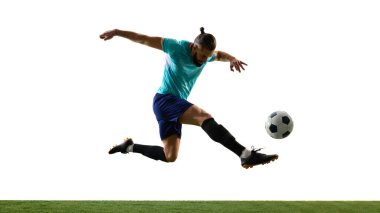 Harekete geçen genç bir futbolcunun dinamik fotoğrafı ve çimenli oyun sahasında beyaz arka planda gol atan golü. Profesyonel spor konsepti, şampiyonluk, maç, zafer.
