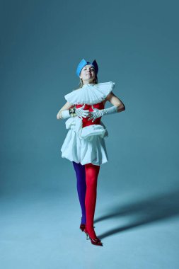 Eksantrik kıyafetli kadın, kendine güvenen kırmızı korse ve heykeltraş eteği, yapılandırılmış zarafet ve oyuncu hareketin karışımını vurguluyor. Denge kavramı, gerçeküstü moda, çeşitlilik.