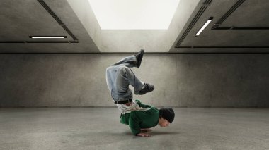 Performans sanatçısı baş aşağı durarak gri beton duvara karşı hareketlerini gösteriyor. Denge kavramı, dans, tempo, güç, şehir havası, hareket halinde tam kontrol.
