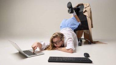 Beyaz stüdyo geçmişine karşı gerçeküstü pozlar veren yaratıcı ofis çalışanı. Stres altında üretken kalmanın zorluğunu temsil ediyor. İş kaosu kavramı, alışılmadık çalışma alanları, dijital aşırı yükleme