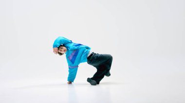 Performans gösteren, klasik giyinen, havada takla atan, beyaz arka plana karşı mükemmel bir hareket, çeviklik gösteren bir sanatçı. Break dans kavramı, güç, yaratıcı güç, müzik, çağdaş sanat.