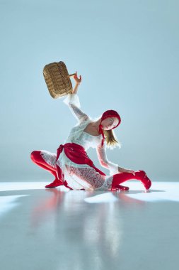 Kadın sepetini kafasının üzerine kaldırıyor, beyaz-kırmızı kıyafet nostaljiyi modernlikle birleştiriyor, yükü ve özgürlüğü simgeliyor. Gerçeküstü kavramı, performans olarak moda, görsel şiir.