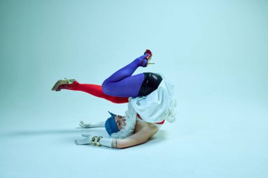 Beklenmedik pozlarda kollarını uzatan kadın, yüksek topuklu ayakkabılar ve hayal gibi hareket eden heykeltraş kıyafeti. Oyuncu moda kavramı, gerçeküstü vücut dili, deneysel fotoğrafçılık, stil..