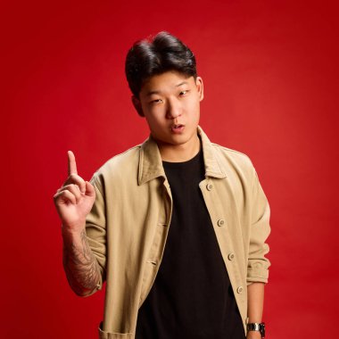 İfade veren genç adamın kendine güvenen bakışlarıyla parmağını kaldırdığı yakın plan. Liderlik kavramı, motivasyon, güven, fikir üretimi, iş iletişimi.