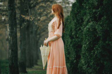 Kestane rengi saçlı, narin, kaliteli elbiseli genç bir kadın elinde fildişi şemsiyeyle uzun köselerin yanında duruyor, sessizlikte kayboluyor. Yalnızlık, fantezi, nostalji. Kitap veya film kapağı için uygun.