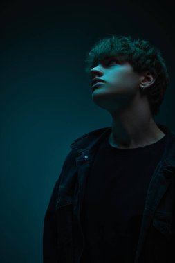 Siyah ceketli genç adam, fütüristik titreşimlerle turuncu ışığa doğru dönüyor. Güzellik ve moda kavramı, kendini ifade etme, insani duygular. Ad