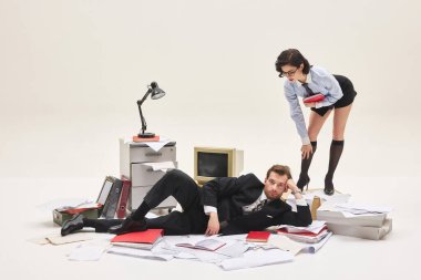 Ofis sahnesinde yerde yatan adama bakarken elinde kırmızı defterle öne doğru eğilen genç bir kadının grup portresi. Ofis hayatı kavramı, insan duyguları, sosyal meseleler, iş.