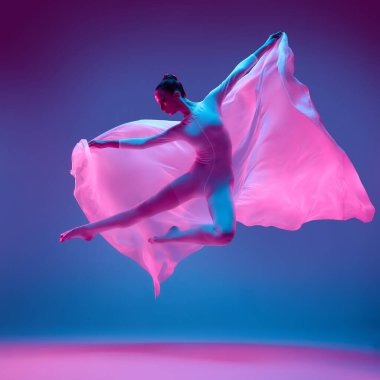 Hareketli bir kadın dansçının hareket halindeki fotoğrafı. Saf kumaşa sarılmış, parlak mavi-pembe arka plana karşı kanat gibi süzülen hareketler. Dans ve özgürlük kavramı, müzik..