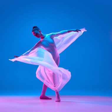 Dansçı, mavi gradyan stüdyo arka planına karşı gerçeküstü neon ışıklarda özgürlüğü ve zarafeti ifade eden kumaş kanatlarla zarif bir spiral hareket yaratır. Hareket kavramı, bale, güzellik, dans.
