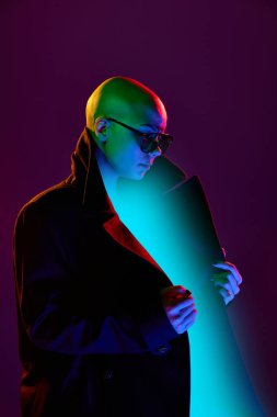 Şık giyinmiş, şık giyinmiş, gözlüklü genç bir kadının yan görünüş portresi açık bir palto ve cyan neon parıltısı taşıyor. Güzellik, moda, fütürizm, tarz, eşitlik kavramı.