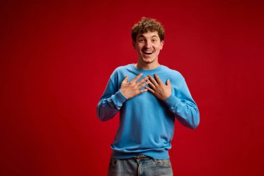 Mutlu, neşeli, geniş gülüşlü iki eliyle göğsüne dokunan genç adam Red Stüdyo 'nun geçmişine karşı minnettarlığını ve neşesini ifade ediyor. Güzellik, duygu, moda, pozitiflik, refah kavramı.