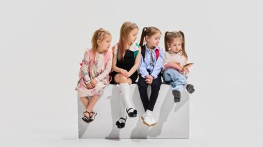 Okul kıyafetli dört kız grubu bankta oturup beyaz stüdyo geçmişine karşı kitap okuyup tartışıyorlar. Öğrenim kavramı, eğitim, okula dönüş, kütüphane, yeni fikirler.