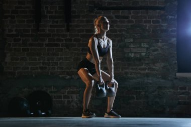 Formda bir kadın spor salonunda duvara yaslanmış, fiziksel güç ve gayret göstererek çömelme hareketi yapıyor. Spor ve kontrol kavramı, fitness, motivasyon, sağlıklı yaşam tarzı, eğitim,.