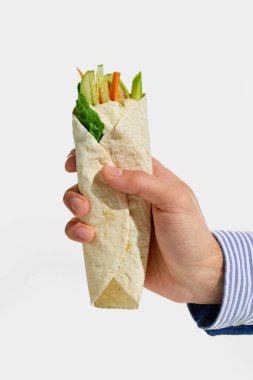 Dilimlenmiş salatalık, havuç, marul ve kremalı sosla dolu taze vejetaryen dürümü beyaz arka planda. Beslenme kavramı, fast food, yemek servisi, paket servis, geleneksel