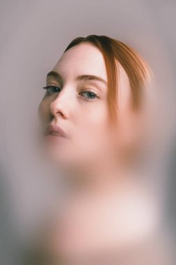 Gerçeküstü kolaj. Kızıl saçlı kadın, şeffaf duvak etkisinden delici gözleriyle yana bakıyor. Soğuk renk tonları uzaklığı ve yansımayı işaret ediyor. Güzellik kavramı, duygu kimliği, portre.