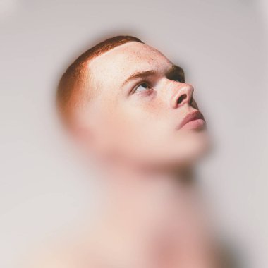 Kavramsal tasarım. Kırmızı bukleli çocuk yukarı bakıyor. Pastel ortamda yoğun bir odak ve yumuşak bulanıklık var. Görüntü merakı, kırılganlığı, büyümeyi yansıtır. Gençlik kavramı, duygu, iç huzur.