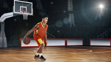 El yapımı kolaj. Kırmızı üniformalı genç sporcu potanın yanında top sürüyor. Basketbol sahasında arka planda seyirciler var. Spor, rekabet, şampiyonluk kavramı.