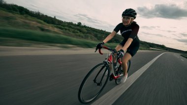 Bisikletçinin kırsal kesimde hız yaparken çekilmiş hareket bulanıklığı, güçlü pedal hareketi, yüzdeki konsantrasyon, asfalt ufukta belirdi. Hız kavramı, itici güç, rekabet.