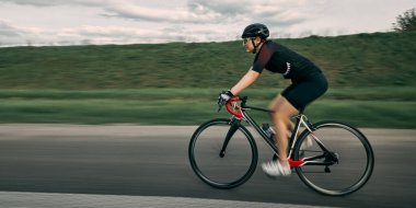 Düşük açılı geniş açılı çekim, dinamik sürüş görüntüsü, hareket bulanıklığı asfalt, net odaklanma ve kararlılıkla ifade edilmiş yüz. Hız, hareket, performans, spor eğitimi kavramı.