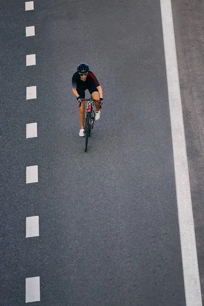 Aerodinamik bisiklet vitesi kullanan atletik kadın şehir otobanındaki şerit çizgileri arasında tek başına dolaşarak kontrolü ve dengeyi sağlıyor. Ekstrem spor kavramı, meydan okuma, hareket, şampiyonluk, antrenman.