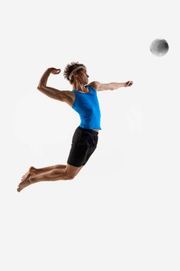 Erkek sporcu voleybolu dinamik bir hareketle ve havadaki enerjiyle beyaz stüdyo arka planına doğru fırlatıyor. Şampiyonluk konsepti, maç, güç, performans