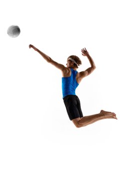 Odaklanmış sporcuların dinamik fotoğrafı atlıyor ve beyaz atölyenin arka planına karşı havada tam güç ve zamanlamayla voleybola uzanıyor. Profesyonel spor etkinliği, oyun, enerji kavramı