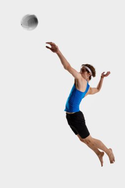 Voleybol oyuncusu, beyaz stüdyo arka planına karşı hızlı oyun sırasında topa vurmak için gergin bir vücutla havada sıçrarken öne uzanıyor. Şampiyonluk kavramı, oyun, yetenek, rekabet