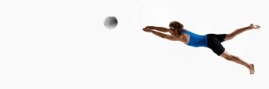 Pankart. Mavi tişörtlü erkek voleybol atleti, beyaz stüdyo arka planına karşı topu engellemek ya da kurtarmak için kollarını uzatarak öne atlıyor. Spor kavramı, şampiyonluk, oyun, güç