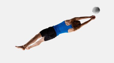 Enerjik adam, voleybol oyuncusu beyaz stüdyo arka planına doğru uçan voleybola odaklanmış bir şekilde havada öne uzanıyor. Hava manzaralı fotoğraf. Eğitim kavramı, spor etkinlikleri, oyun, amaç