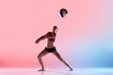 Dişi voleybol atleti geniş duruş içinde voleybol oynamaya hazır pembe-mavi ışıklar altında gradyan stüdyo arka planına karşı. Spor, hazırlık, kontrol ve strateji kavramı, turnuva.