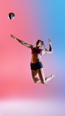 Voleybol oynamak üzere olan bayan sporcunun dinamik fotoğrafı gradyan stüdyo arka planına çift renkli neon ışığı yansıtıyor. Güç kavramı, zamanlama ve patlayıcı güç spor, hareket
