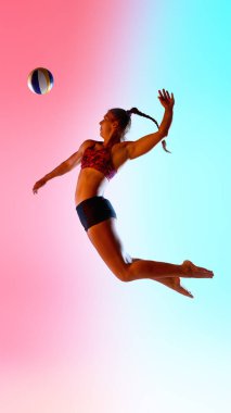 Yandan bakan kadın sporcunun dinamik fotoğrafı voleybol topuna havadayken canlı neon ışığı altında sıçrıyor ve gradyan stüdyo arkaplanı kazanıyor. Spor anlayışı, voleybol gücü, çeviklik ve atletik hareket.